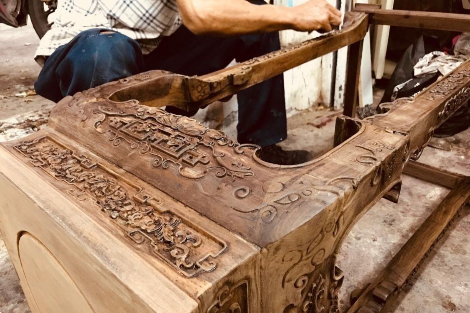 A man carefully crafting a wooden chair in a well-lit workshop, surrounded by tools and wood materials.
