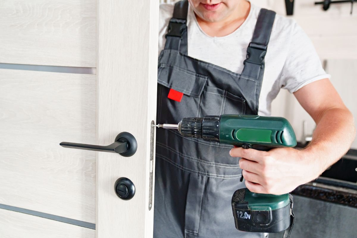 A man in overalls stands with a drill, focused on furniture repair services.